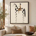 Framed wall art hanging above a beige sofa in a styled living room. The artwork shows a stylized black-and-cream horse with a rider in tan and black, enclosed in a dark frame.